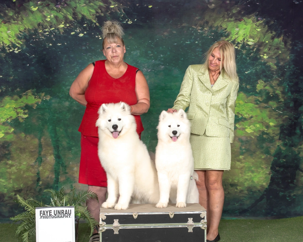 Two women and a white dog posing for the camera.