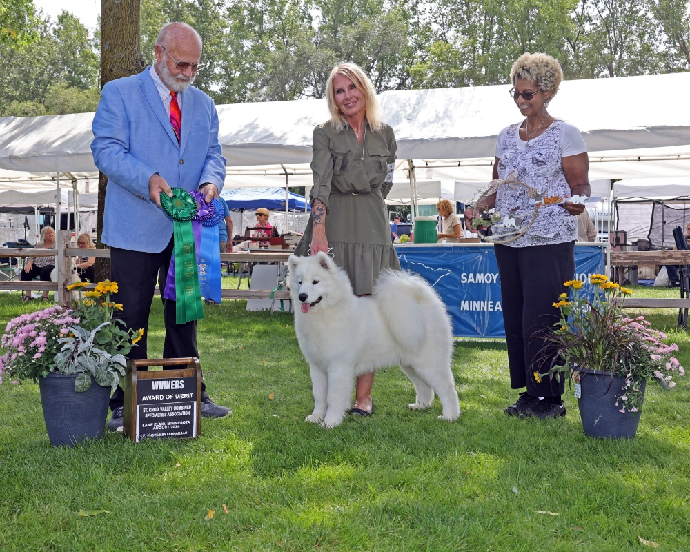 A man and two women holding a white dog.